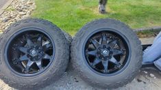 two black wheels and tires sitting on the ground