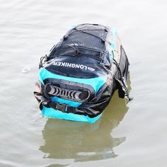 a blue and black bag floating on top of water