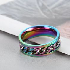 a rainbow colored ring sitting on top of a white table next to a piece of paper