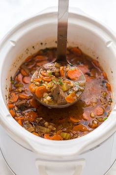 a spoon full of soup with carrots, beans and meat in an instant pot