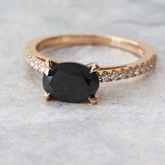 an engagement ring with a black diamond in the center and white diamonds on the sides