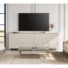 a living room with white furniture and a flat screen tv mounted on the wall above it