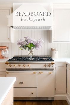 a kitchen with white cabinets and pink flowers in a vase on the stove top that says beadboard backsplash