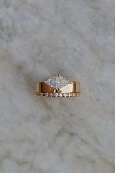 a gold ring with two diamonds on it sitting on a white marble countertop,