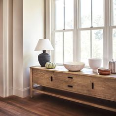 a table with two bowls and a lamp on it in front of a large window