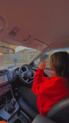 a woman in a red jacket driving a car