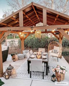 an outdoor dining area with wicker furniture and lights on the ceiling, surrounded by greenery