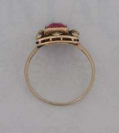 Ladies 10 karat synthetic ruby ring. The ring contains a rectangular ruby surrounded by a filigree shadow box with small gold ornamental knobs at the corners and at the center points of the milgrain edged box. The edwardian style antiqued ring is size 5.25. Antique Red Signet Ring In 14k Gold, Antique Red 14k Gold Signet Ring, Antique Red Ruby Ring In 14k Gold, Victorian 14k Gold Ruby Ring With Intricate Design, Antique Hallmarked Ruby Signet Ring, Vintage Gold Ruby Ring With Filigree, Antique Gold Ruby Ring With Filigree, Antique 14k Gold Ruby Ring With Intricate Design, Antique Ruby Signet Ring