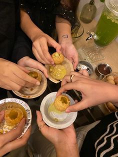 several people are holding small plates with food on them while sitting at a table together