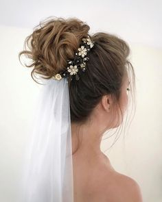 a woman wearing a bridal veil with flowers on it's head and hair comb in her hair