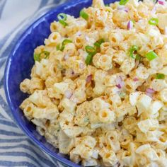 a blue bowl filled with macaroni salad on top of a striped table cloth