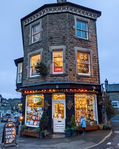 an old brick building with shops on the front and windows lit up at night time