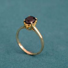 a gold ring with a brown stone in the center on a blue tablecloth background