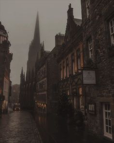 an old city street with tall buildings on both sides and a clock tower in the distance