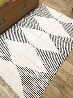 a white and black rug on the floor in a room with a bed next to it