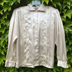 A 1980s Sonya Ratay satin polyester blouse in a classic cream with lace trimmed collar and front tucks.  From a Cincinnati estate  Excellent vintage condition  Size 6 Satin Collared Blouse For Daywear, Collared Satin Blouse For Daywear, Formal Cream Satin Top, Cream Satin Top For Formal Occasions, Cream Satin Tops For Formal Occasions, Cream Satin Long Sleeve Blouse, Vintage Silk Collared Top, Classic Cream Blouse With Ruffled Collar, Elegant Cream Top With Peter Pan Collar