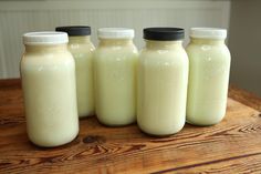 four bottles of milk sitting on top of a wooden table