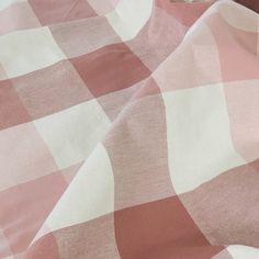 a pink and white checkered blanket laying on top of a bed