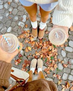 two people standing on the ground with their feet up and drinking water from plastic cups