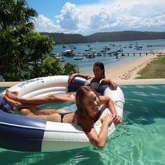 two women are floating on inflatable rafts near the beach