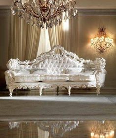 an ornate white couch with crystal chandelier hanging from it's center wall