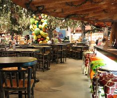 the inside of a restaurant with tables, chairs and fruit hanging from the ceiling above