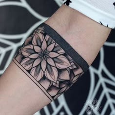 a black and white photo of a flower tattoo on the left arm with an intricate design