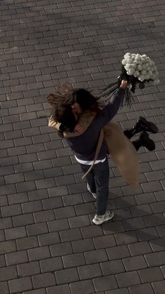 a woman is holding flowers while walking down the street