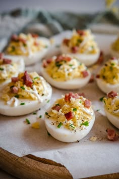 deviled eggs with bacon and chives on a cutting board, ready to be eaten