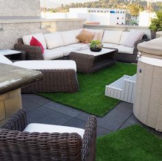 an outdoor living area with wicker furniture and artificial grass on the roof top deck