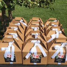 several boxes with white ribbons tied to them sitting on a table in front of a tree