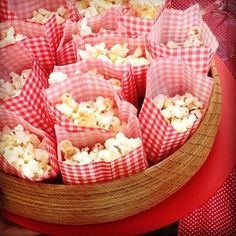 red and white checkered paper bags filled with popcorn sitting in a wicker basket