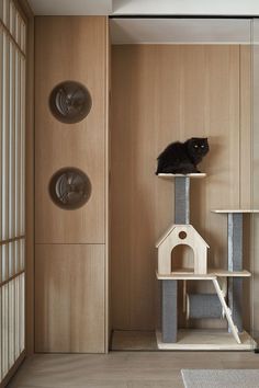 a black cat sitting on top of a scratching post in a room with wood paneling