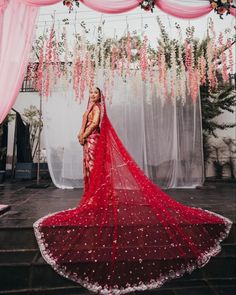 a woman in a red sari standing under a canopy