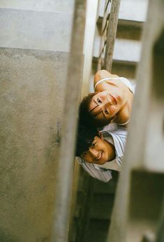 two people standing next to each other on the side of stairs with their heads together