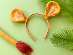 a mouse ears headband with a red tassel and palm leaves on a green background