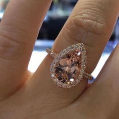 a woman's engagement ring with an oval shaped morganite and diamond halos