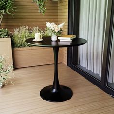 a small table on a wooden floor next to some potted plants and a window