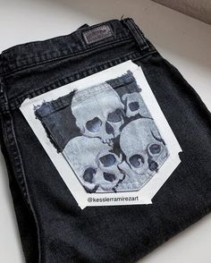 a pair of black jeans with skulls on the front and back pocket are sitting on a white surface