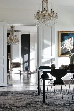 an elegant dining room with chandelier and art work on the wall behind it