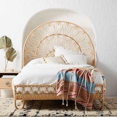 the bed is made up with white linens and wicker headboard, along with an intricately woven blanket