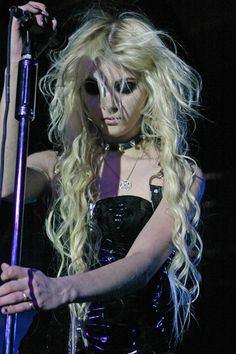 a woman with long blonde hair holding a microphone