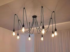 a bunch of light bulbs hanging from the ceiling in a room with curtains and drapes