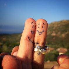 two fingers with smiley faces drawn on them, one has a ring in the other's hand