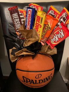 a basketball sitting on top of a black chair next to candy bar wrappers and candies