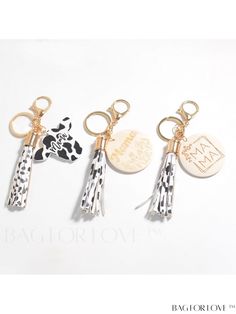 three keychains with different designs on them, one has a cow and the other has a giraffe