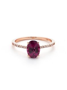 a pink tourmaline ring with diamonds on the band and an oval cut stone in the center