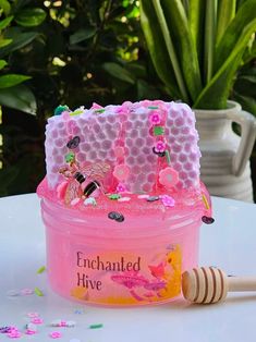 a pink container sitting on top of a white table next to a wooden honey comb