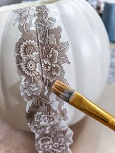 a white pumpkin decorated with lace and a brush