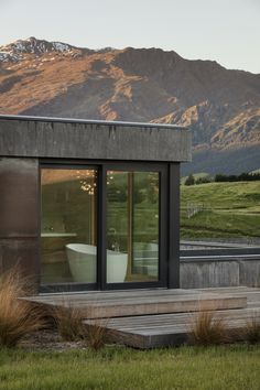 the outside of a house with mountains in the back ground and grass on the side